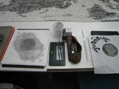 work table showing 'letters from the bank' and two commemorative handkerchiefs - pencil on cloth hanky, and ink on paper hanky