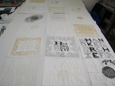 work table showing commemorative handkerchiefs - ink, pencil and laser cut paper hankies